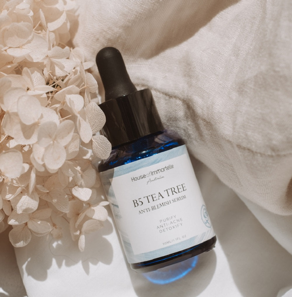 House of Immortelle B5 Tea Tree Anti-Blemish Serum in a sleek bottle, formulated with tea tree oil and vitamin B5 to target blemishes and soothe the skin. This lightweight serum helps reduce the appearance of acne and blemishes, leaving the skin clear and balanced