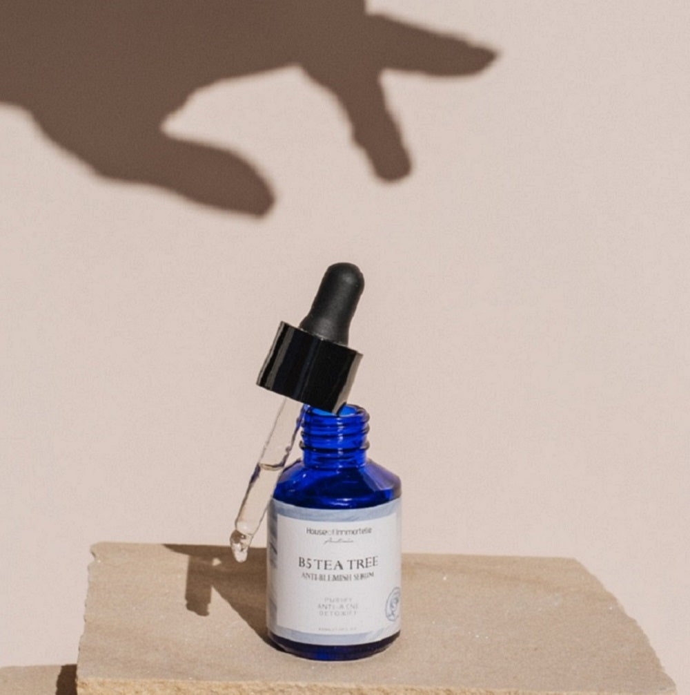 House of Immortelle B5 Tea Tree Anti-Blemish Serum in a sleek bottle, formulated with tea tree oil and vitamin B5 to target blemishes and soothe the skin. This lightweight serum helps reduce the appearance of acne and blemishes, leaving the skin clear and balanced