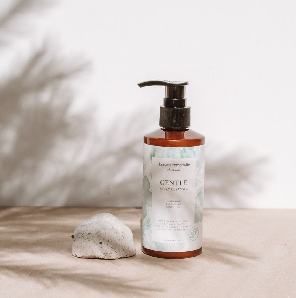 House of Immortelle Gentle Milky Cleanser in a smooth bottle, featuring a creamy formula designed to cleanse and hydrate the skin. This mild cleanser gently removes impurities while nourishing, leaving the skin soft, refreshed, and balanced