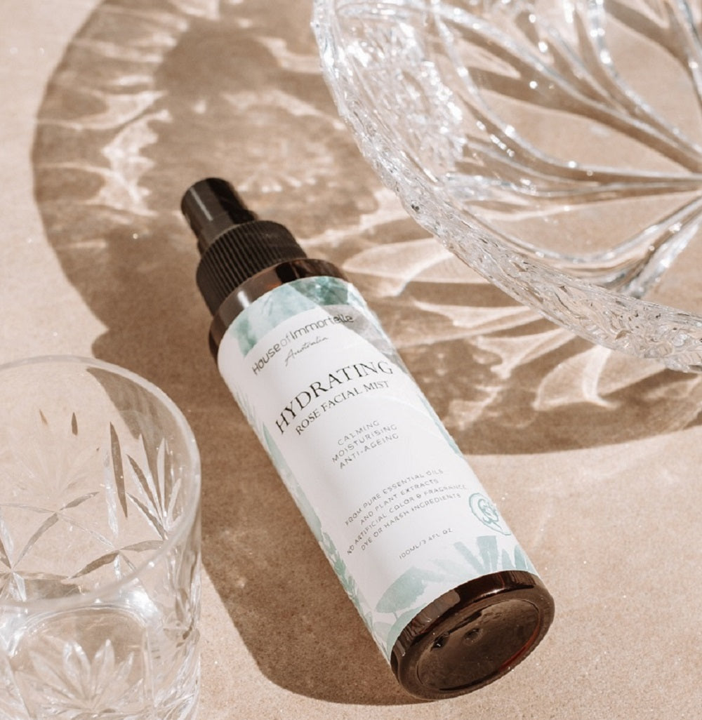 House of Immortelle Hydrating Rose Facial Mist in a sleek spray bottle, infused with rose extract to refresh and hydrate the skin. This mist provides a soothing, dewy glow, perfect for revitalizing the skin throughout the day or setting makeup