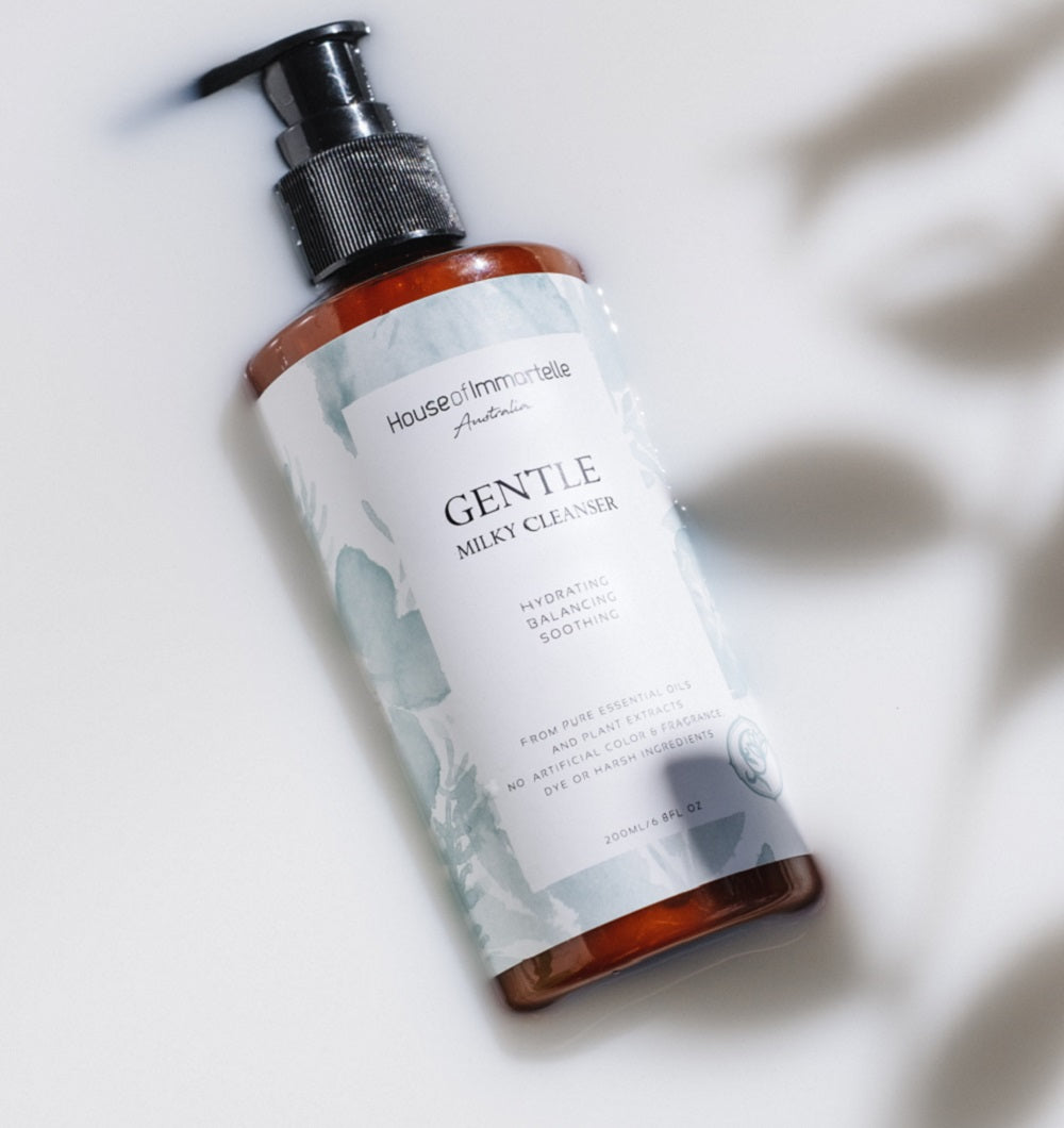 House of Immortelle Gentle Milky Cleanser in a smooth bottle, featuring a creamy formula designed to cleanse and hydrate the skin. This mild cleanser gently removes impurities while nourishing, leaving the skin soft, refreshed, and balanced