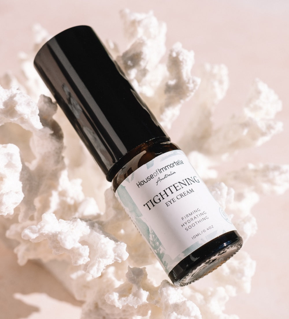 A potent Tightening Eye Cream by House of Immortelle, formulated to firm and smooth the delicate skin around the eyes. This rich cream helps reduce the appearance of fine lines, puffiness, and dark circles, leaving the eyes looking rejuvenated and refreshed. Packaged in a luxurious container for daily use.